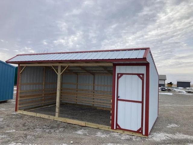 A white shed with a red roof is sitting in a parking lot.