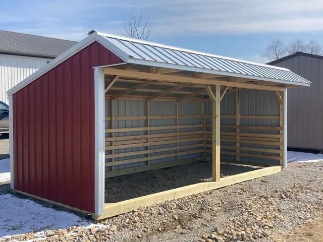 A red barn with a white roof is sitting in the snow.
