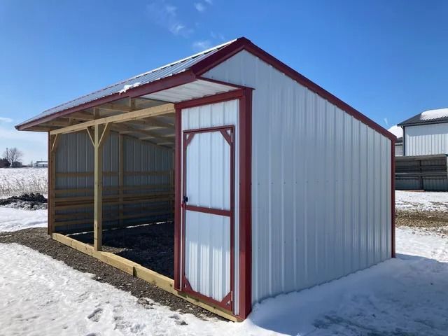 A white shed with a red trim is sitting in the snow.