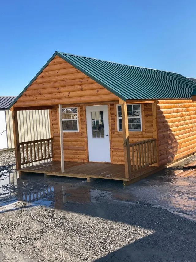 A small wooden cabin with a green roof and porch.
