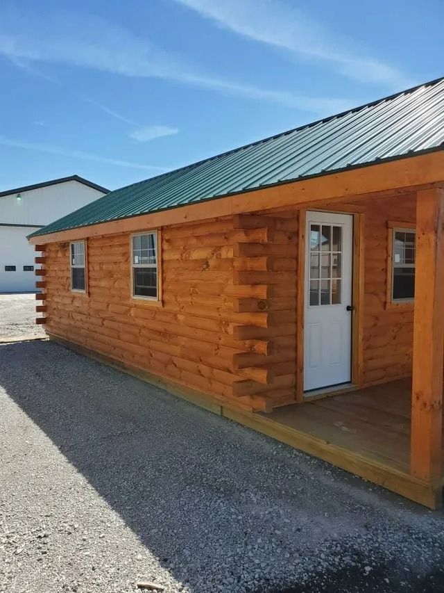 A log cabin with a porch and a green roof