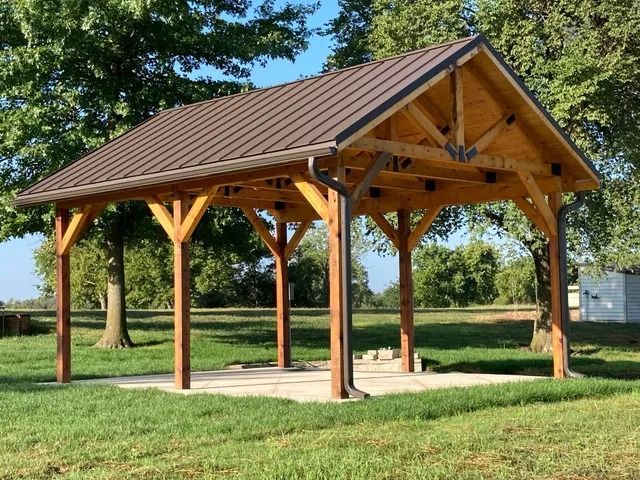 A wooden pavilion with a brown roof in a park