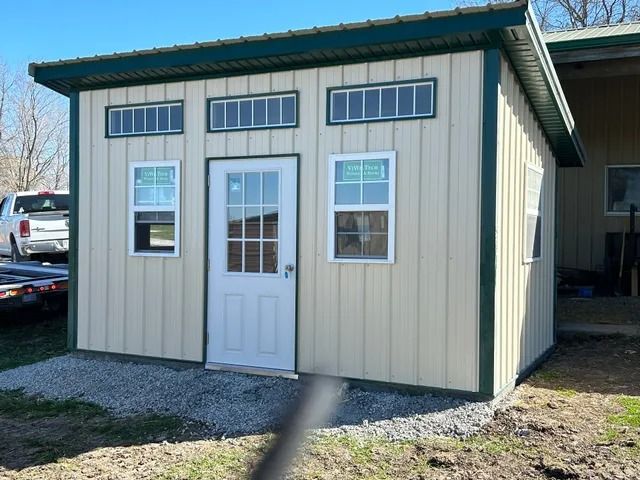 A small shed with a green roof and a white door