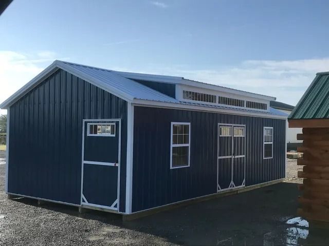 A blue shed with white trim and a green roof