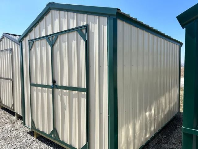 A white metal shed with green trim and doors