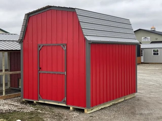 A red barn with a gray roof is sitting on top of a wooden pallet.