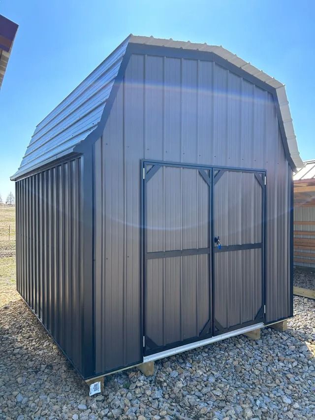A barn shed is sitting on top of a pile of rocks.