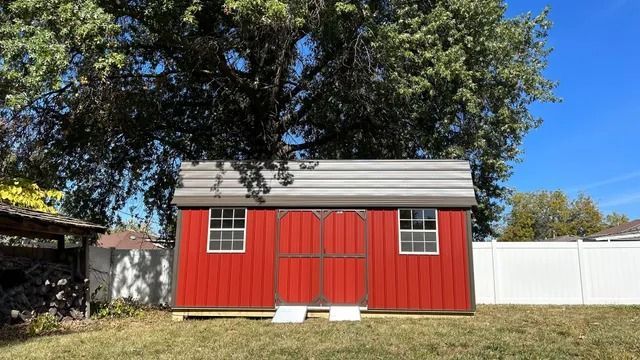 A red shed with a white fence in the backyard.
