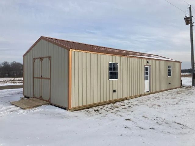 A large metal building is sitting in the middle of a snowy field.