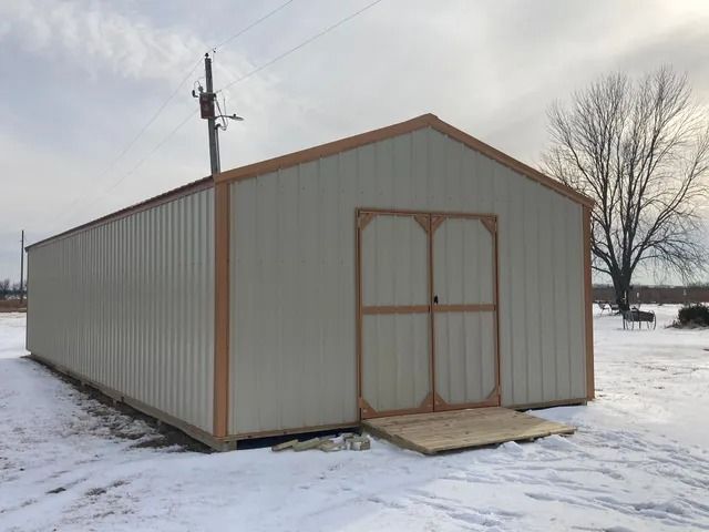 A shed is sitting in the middle of a snowy field.