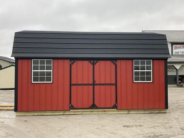 A red shed with a black roof is sitting in a parking lot.