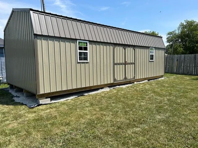 A shed is sitting in the middle of a lush green field.