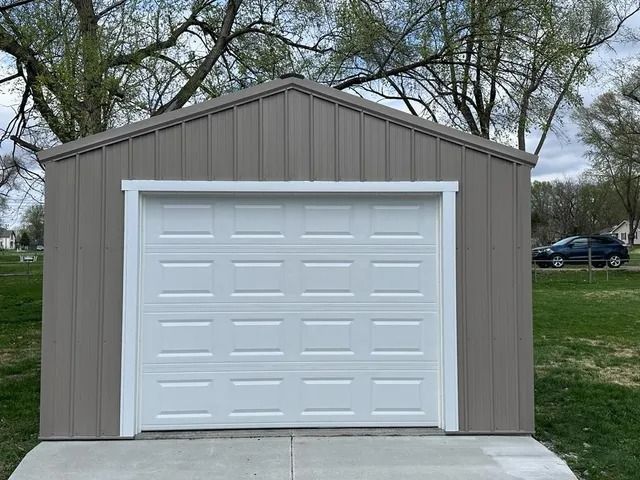A garage with a white garage door and a car parked in front of it.