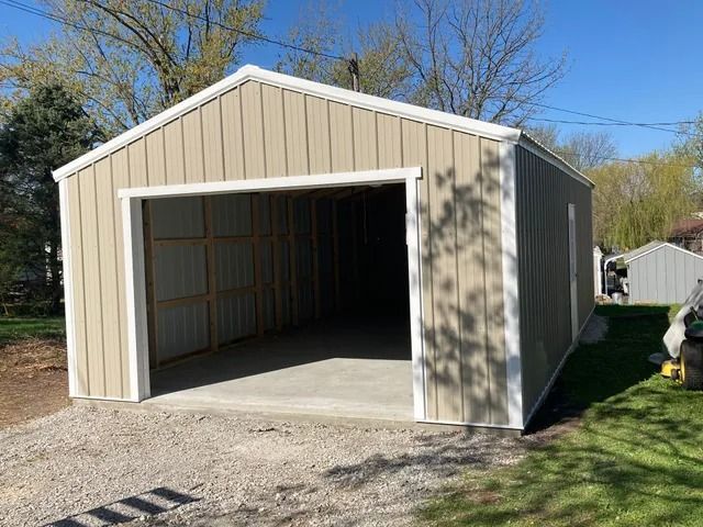 A tan metal garage with a white trim and a concrete floor.