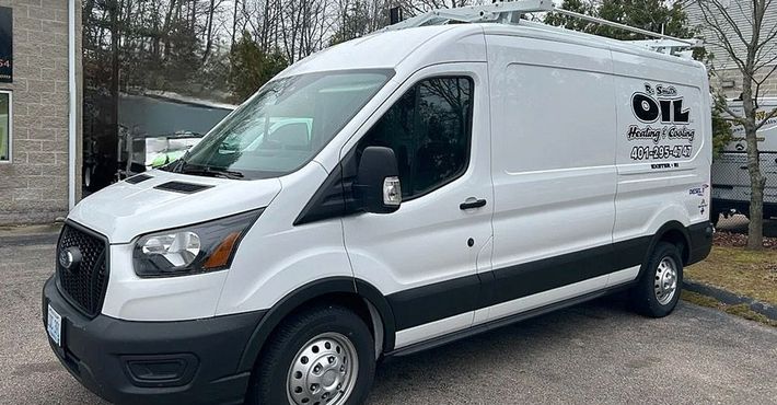 A white van is parked in a parking lot in front of a building.