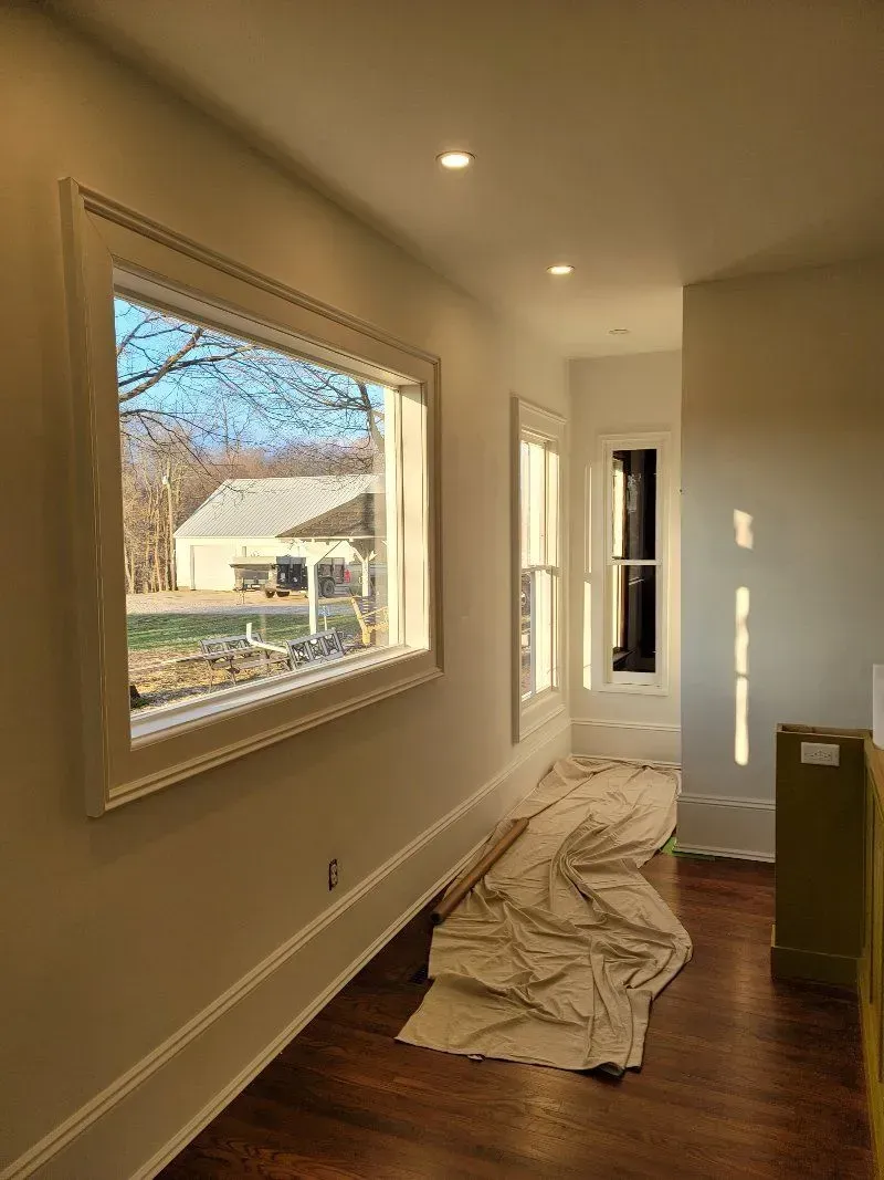Hallway with a large window and two smaller windows, showing a bright outdoor scene.