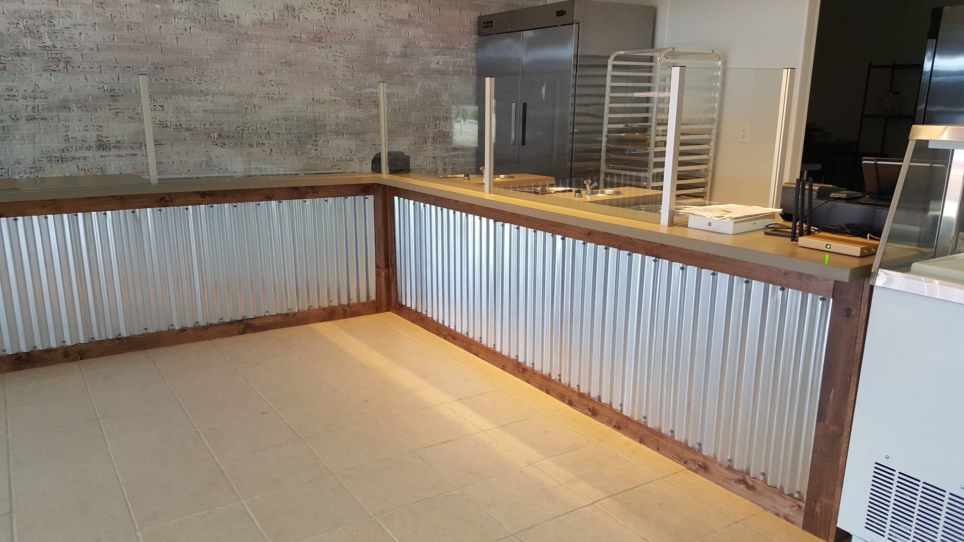 Counter with corrugated metal siding and wood trim, next to an empty room with stainless steel appliances.