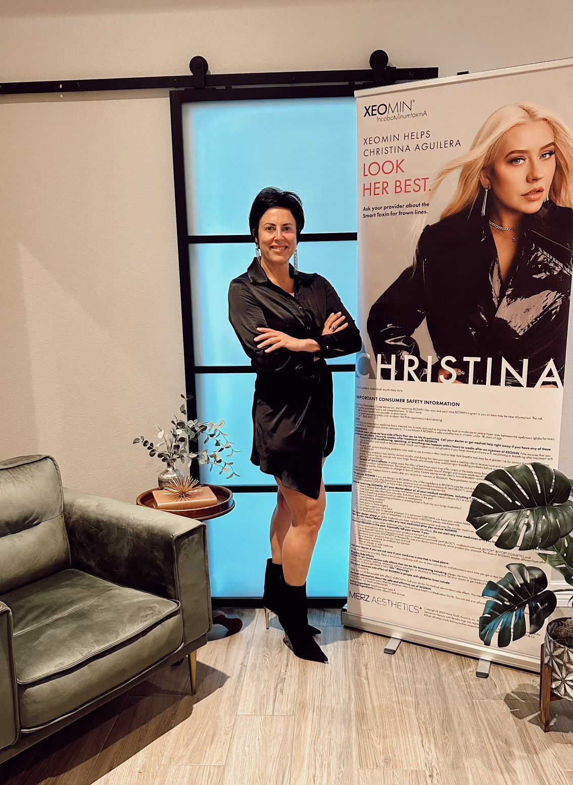 a woman in a black dress is standing in front of a poster .