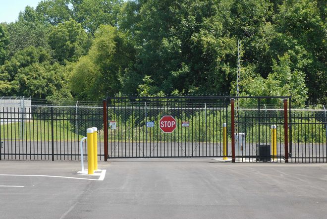 A security gate with a stop sign, in front of a wooded area.