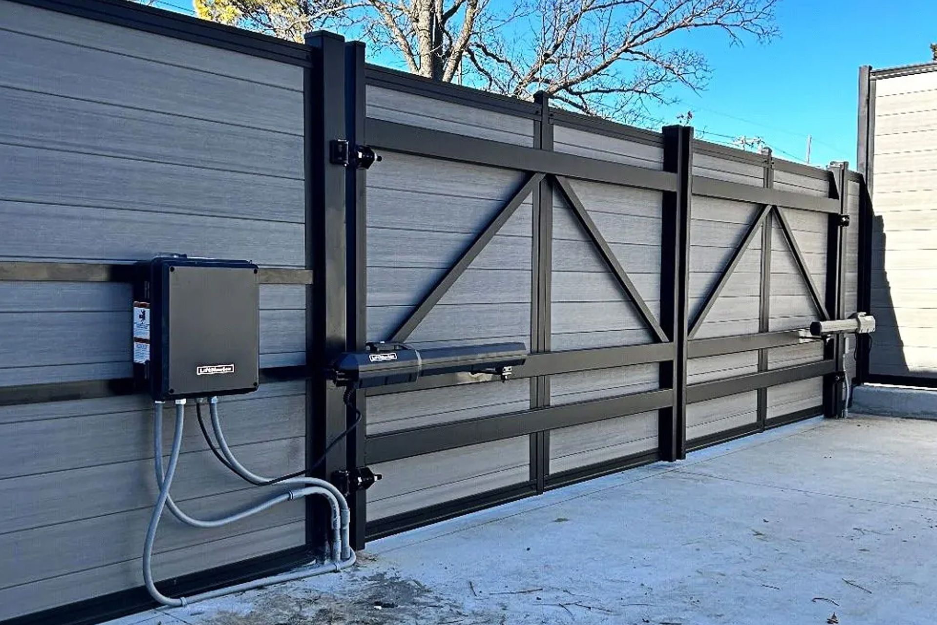 Automated gray and black gate with motor and wiring.