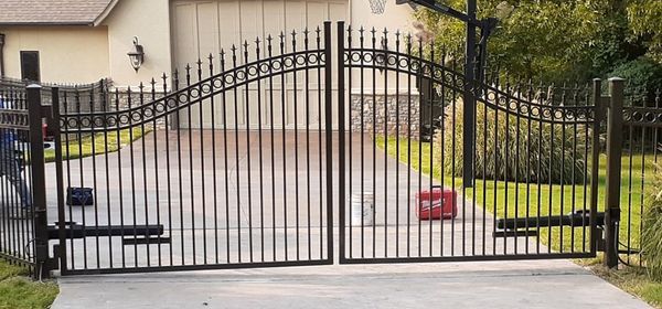 Black iron gate in front of a house. The gate is closed.