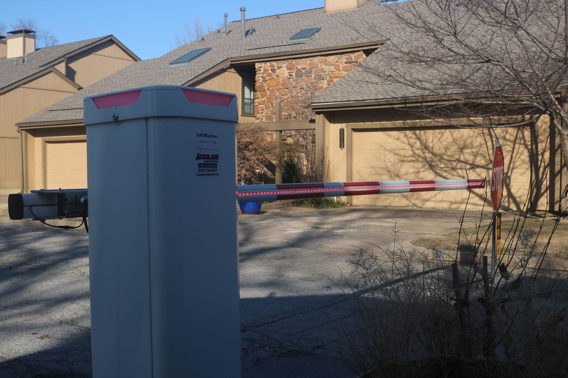 A security gate arm blocks access to a driveway in front of multi-story residential buildings.