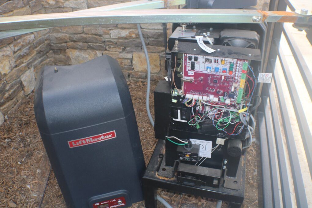 Open LiftMaster gate operator motor with its grey cover removed, revealing internal circuit boards and wiring.