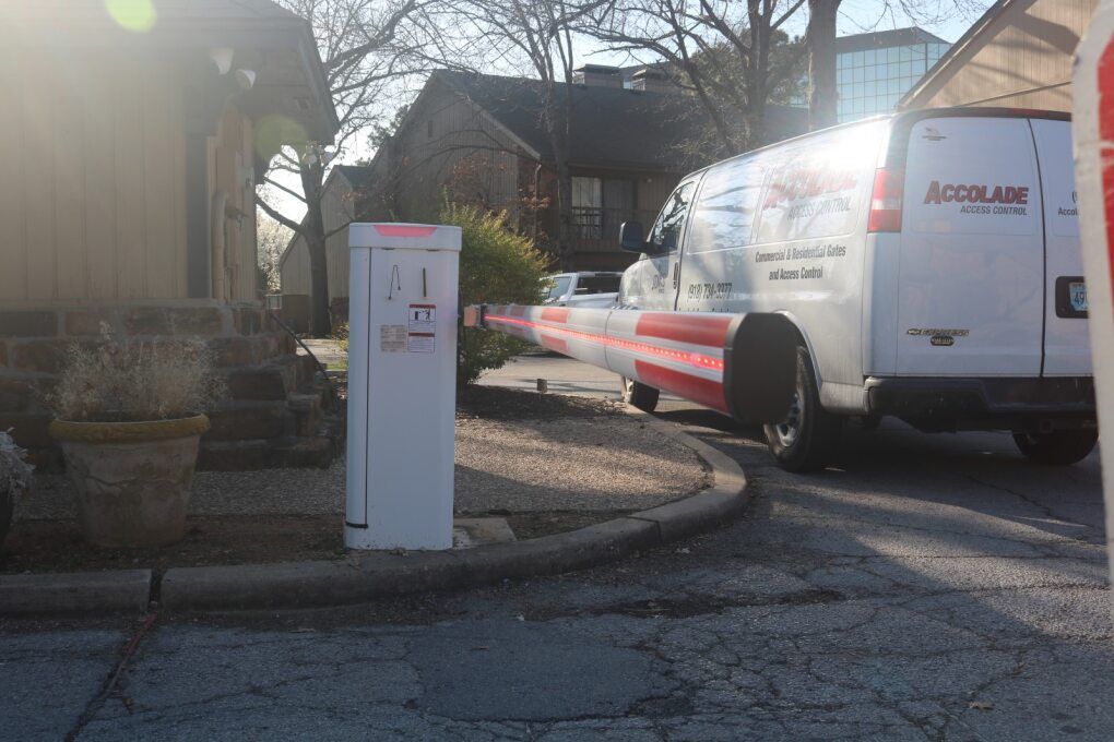 An Accolade service van is partially blocked by a red and white striped security gate at the entrance to a parking area.