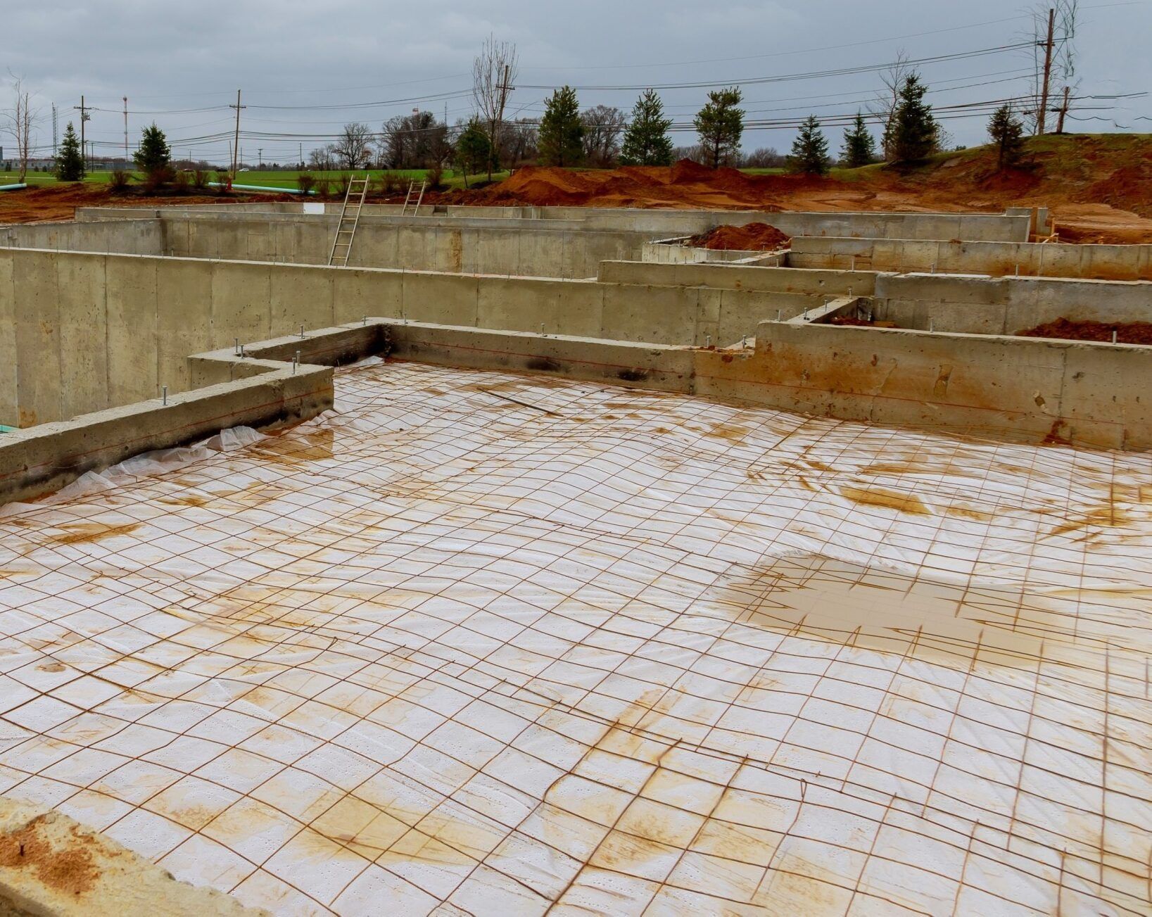 Construction site with concrete foundation and wire mesh laid across the base, ready for pouring a floor.