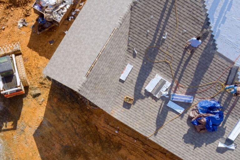 Overhead view of a house roof under construction; a construction worker and equipment are present.