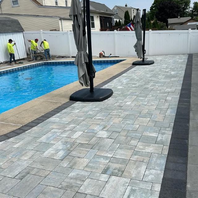 A patio with umbrellas and a pool in the background