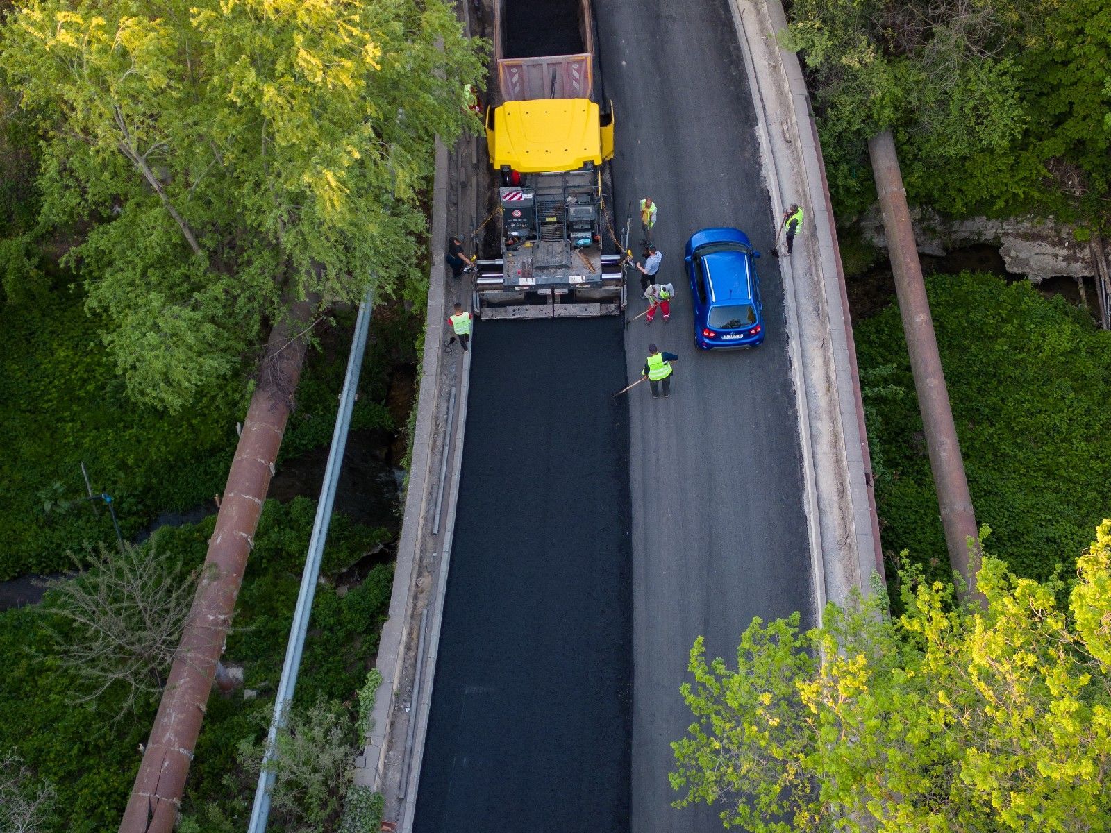 An aerial view of a road being paved with a truck.