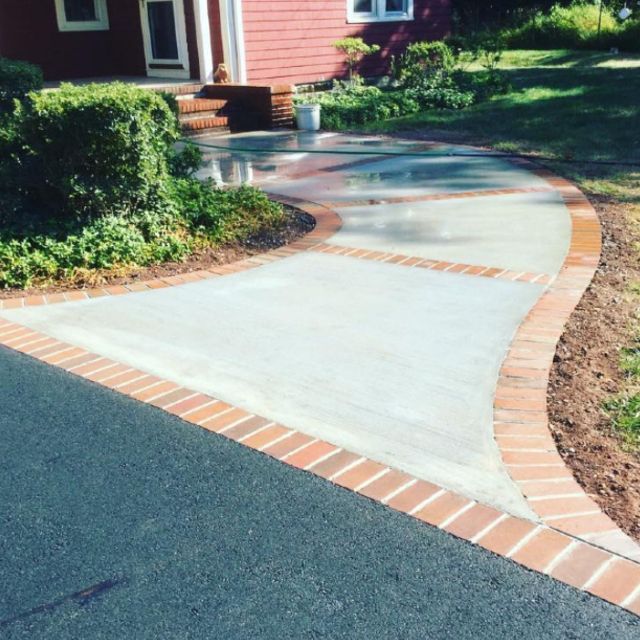 A brick walkway leading to a red house