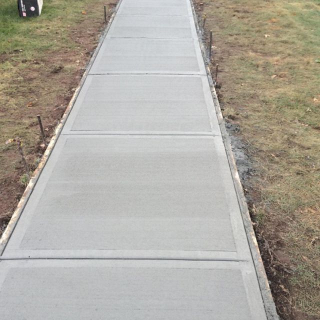 A long concrete walkway going through a grassy area.