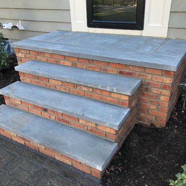 Brick steps leading to a door with grey stone treads and a brick base.