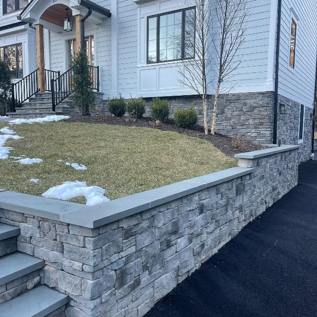 A white house with a stone wall in front of it