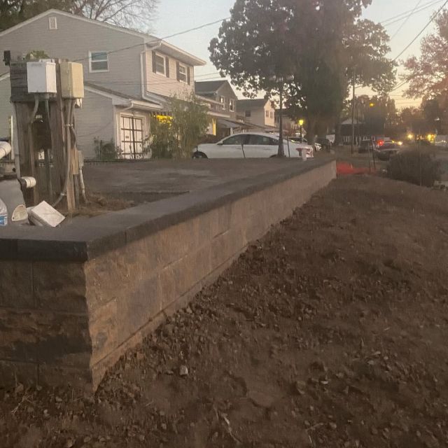 A white house with a stone wall in front of it