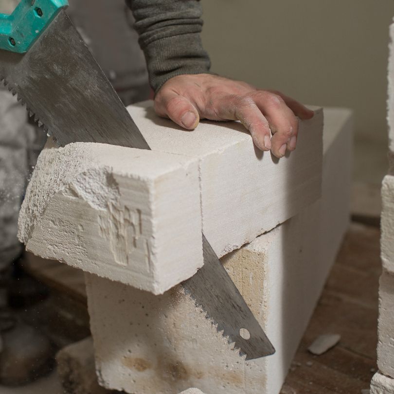 A person is cutting a brick with a saw