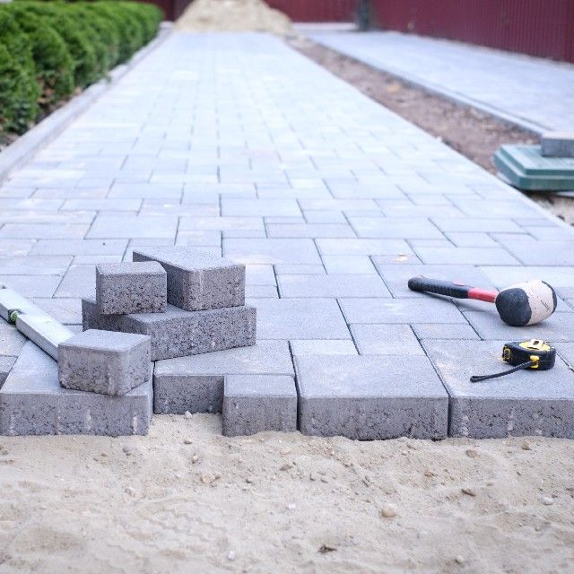 A walkway is being built with bricks and tools on the ground.