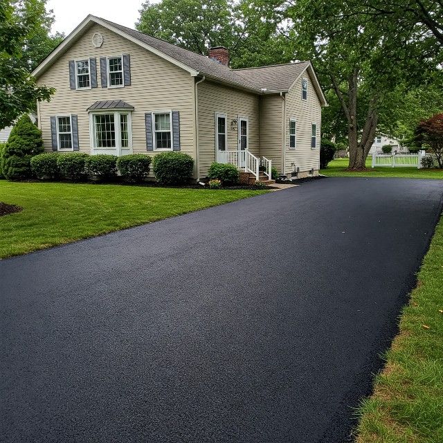 A large house with a black driveway leading to it.