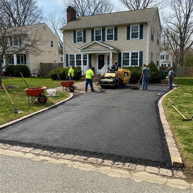 A group of people are working on a driveway in front of a house
