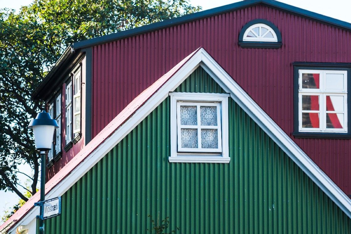 A green house with a red roof and a white window