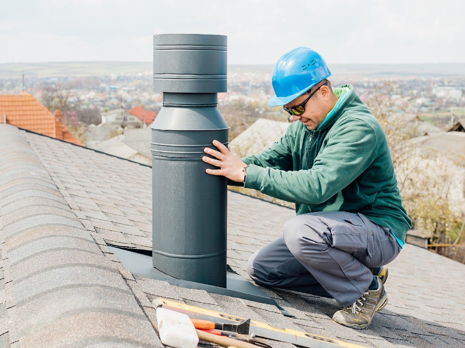 A man is installing a chimney on the roof of a house.