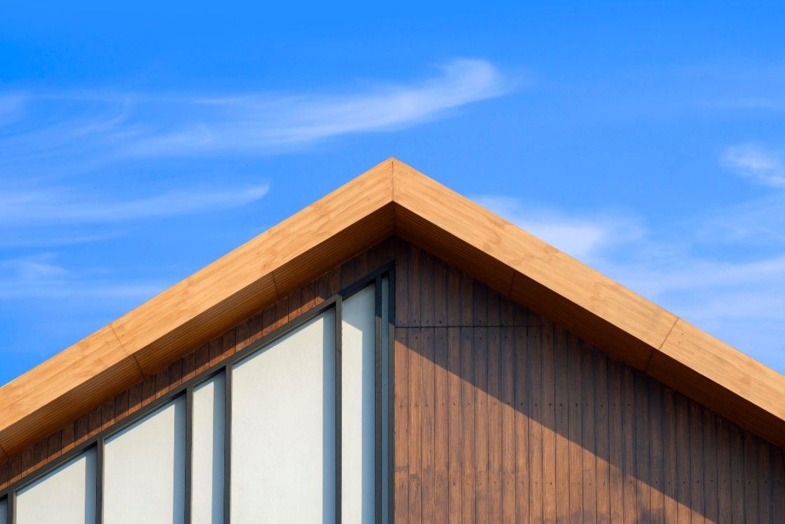 A house with a wooden roof and a blue sky in the background.