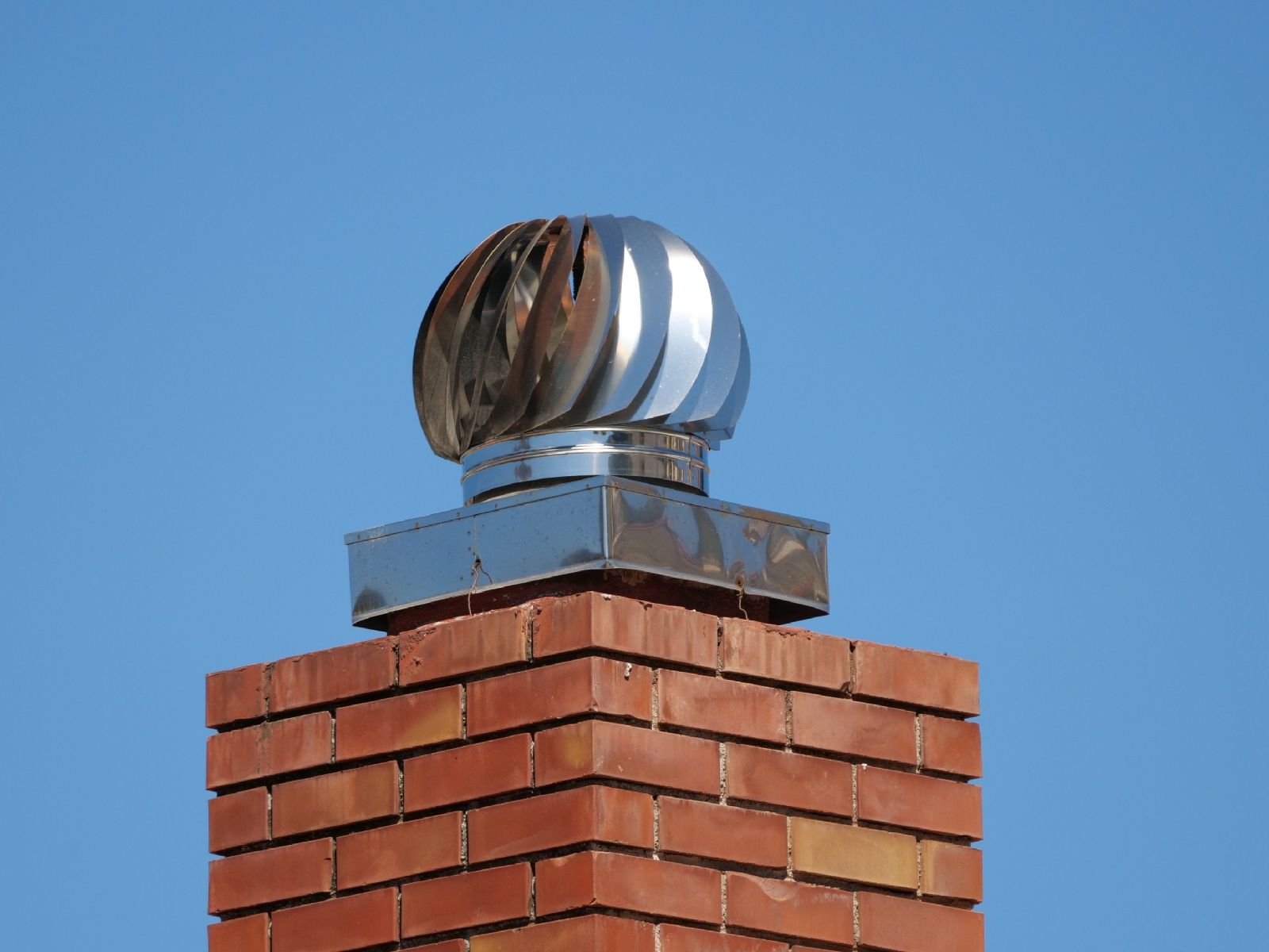 A brick chimney with a wind turbine on top of it