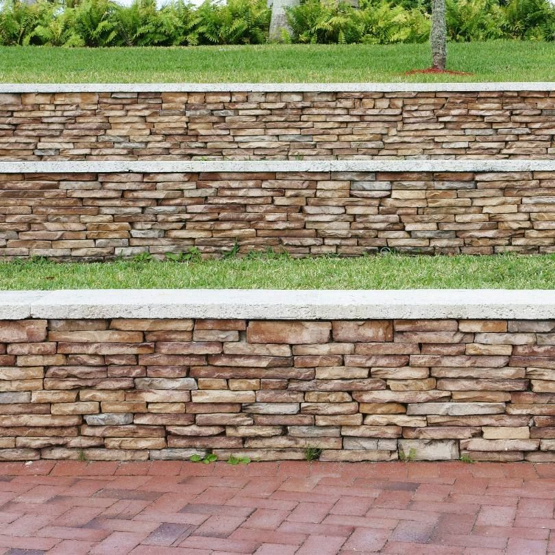 A stone wall with steps leading up to a grassy area.