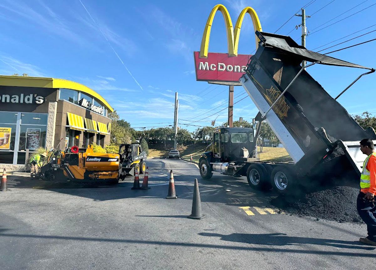 A dump truck unloading asphalt in front of a restaurant