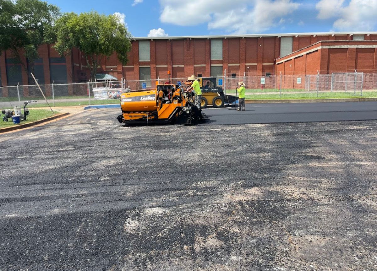 A group of construction workers laying asphalt in a parking lot