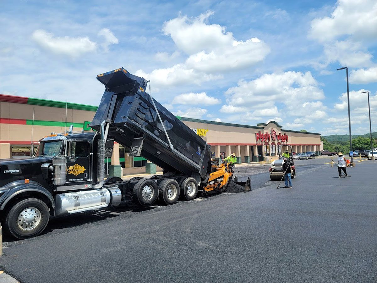 A dump truck unloading asphalt in front of a building