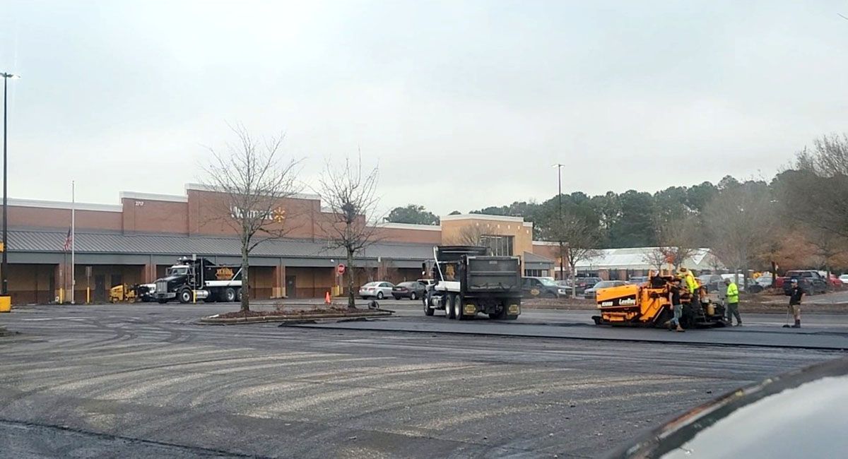 A parking lot is being paved in front of a building